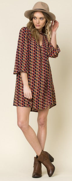 Bunt gemustertes Shirt-Kleid mit V-Ausschnitt und Dreiviertelärmeln, kombiniert mit Hut und Stiefeletten.