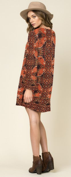 Oranges, langärmliges Kleid mit auffälligem Muster, lockerem Schnitt und hohem Kragen.