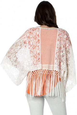 Weißer Spitzen-Kimono mit orangefarbenen Fransen und besticktem Rückeneinsatz, über Jeans getragen.