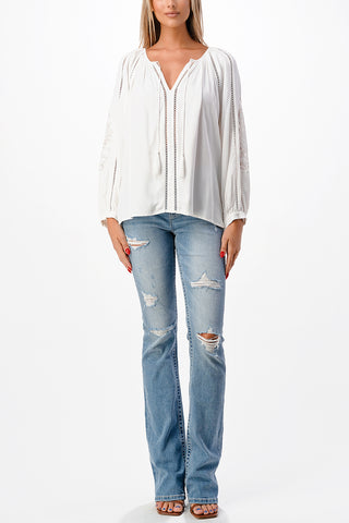 Weißes, locker geschnittenes Shirt mit V-Ausschnitt und langen Ärmeln zu bestickter Jeans.